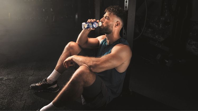 Mann trinkt im Gym Emmi Energy Milk